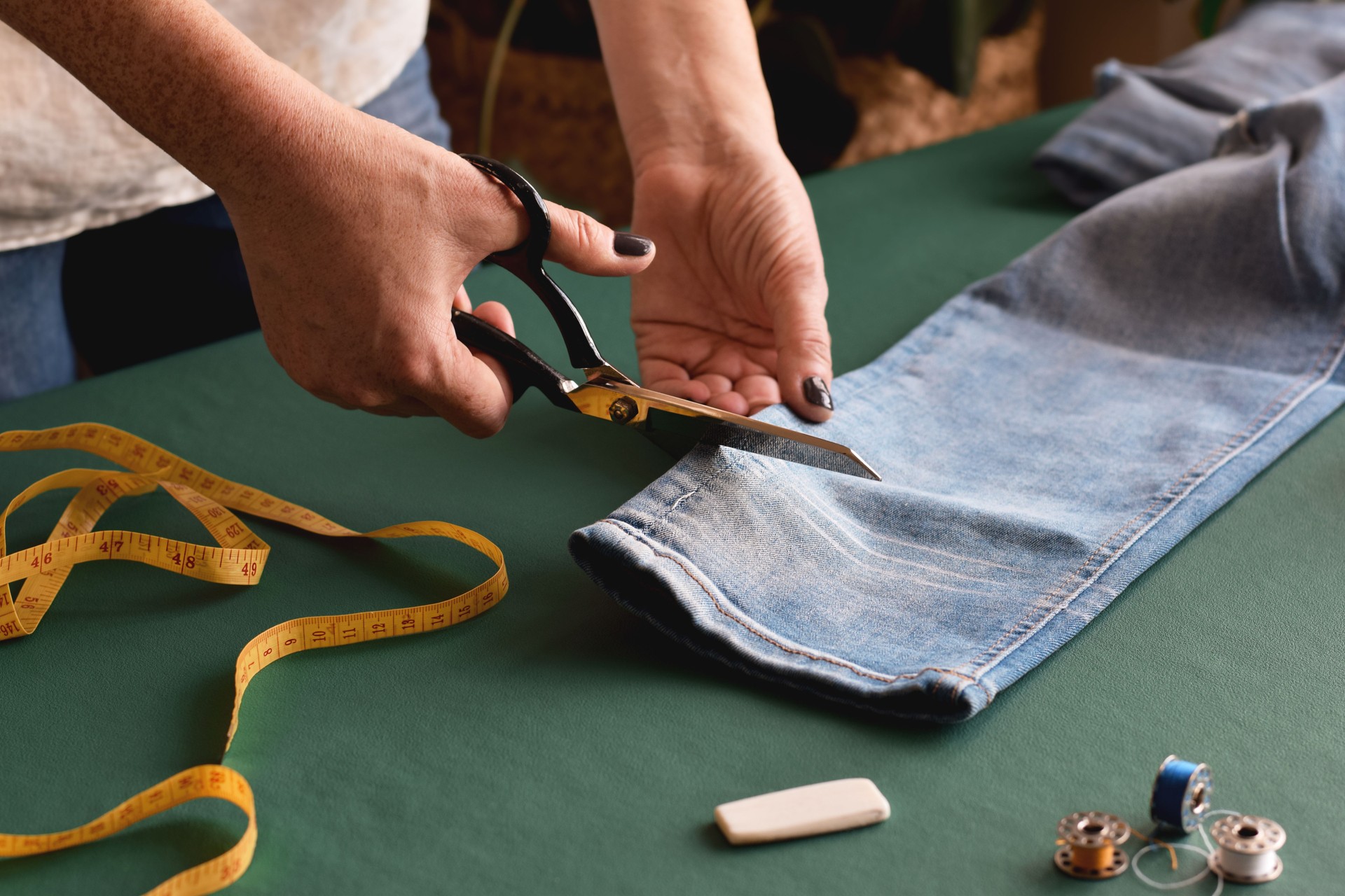 Seamstress using scissors to cut jeans for hemming